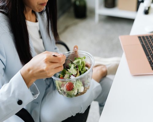 A person eating a salad slowly by a window