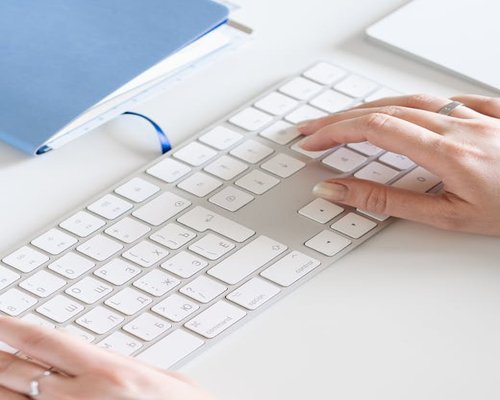 Hands resting on a desk next to a keyboard, taking a pause